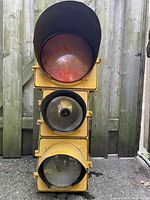 Front view of used yellow metal traffic light prop with visible red, reflective, and white lenses.
