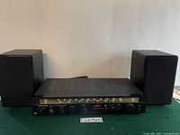 Full view of the Realistic STA-100 receiver with two bookshelf speakers on either side, showing overall condition and size.