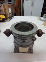 Front view of U.S. Navy ship compass showing metal body, compensating balls, and mounted base.