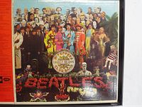 Front cover of the original Sgt. Pepper album jacket showing the colorful group portrait and collage of figures with floral lettering 'BEATLES'.