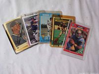 Photo showing all five sports cards in protective sleeves: autographed Goose Gossage card, autographed Brett Boone card, Topps Super Rookie Troy Aikman, Pros Set Troy Aikman prospect card, and 1971 Topps Roman Gabriel card.