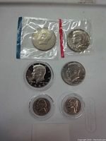 Photo of the full collection showing six coins including four Kennedy half dollars and two Jefferson nickels, some in plastic capsules or mint cellophane.