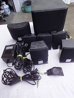 Full set of speakers, subwoofer, control module, cables, and power adapter arranged on a surface