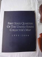 Blue hardcover collector's map closed, showing title and date range 1999-2008 with gold corner protectors.