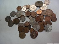 Photo showing a variety of British Commonwealth coins mostly in silver and copper colors, including pennies and larger silver coins.