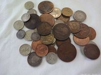 Group of 26 British Commonwealth coins mixed copper and silver colored scattered on white fabric background