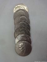 Seven circulated Eisenhower silver dollar coins laid in a row showing obverse sides with Eisenhower's profile and visible dates.
