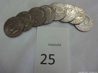 Front and back views of eight circulated Eisenhower silver dollar coins arranged in an arc, showing their obverse and reverse surfaces.