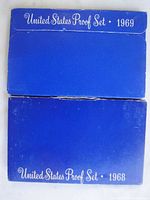 Original blue cardboard boxes labeled 'United States Proof Set 1968' and 'United States Proof Set 1969' showing exterior packaging of the proof sets.