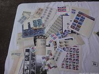 Overview of large assortment of US postage stamps in various sheets and strips laid out on white surface