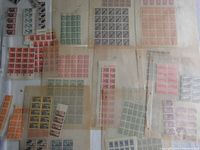 A wide assortment of vintage foreign postage stamps in sheets and blocks, showing various colors and denominations mostly in red, green, yellow and purple tones.