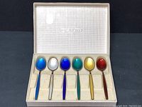 Full set of 6 multicolored enamel demitasse spoons arranged in original box with molded inserts.