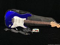 Full front view of blue Squier Strat electric guitar with accessories
