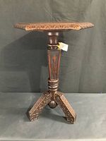 Full view of hexagonal side table showing shaped top and carved pedestal and legs.