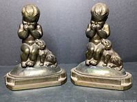 Front view of the pair of cast metal bookends showing a giggling child and dog on each.