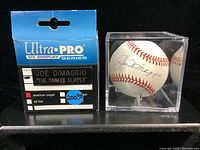 Front view of packaging next to signed baseball in display case