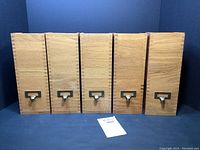 Front view of the five oak vertical file boxes arranged in a row showing brass label holders and dovetail joints