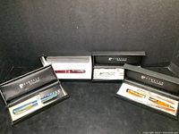 All four pens in their respective presentation boxes on black background