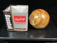 Photo showing the official Rawlings American League baseball with red stitching and the original box branded with Rawlings and Baseball American League text.