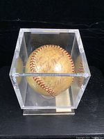 Front view of the signed baseball inside clear acrylic display case showing multiple signatures.