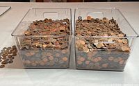 Two clear plastic bins filled with loose pennies