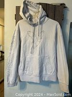 White American Eagle hoodie hanging on door, front view showing bird graphic and text on sleeve