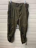 Photo of women's dark green capris showing front pockets, stitched knee detailing, and ruched hems with tie closures.
