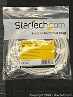 Clear image of sealed StarTech.com package containing a white Cat 6 Ethernet patch cable, showing full packaging and cable coiled inside.