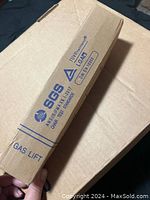 Rectangular cardboard box imprinted with SGS and TÜV Rheinland certification logos, marked as a gas lift for chair lifts.