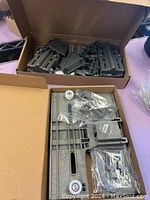 Two cardboard boxes containing plastic dishwasher upper adjustment components.