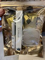 Clear golden resealable bag with all contents of the nail set visible, held in hand showing contents and packaging.