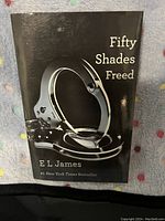 Front cover of the softcover book 'Fifty Shades Freed' showing the title, author's name, and handcuffs image on a black background.