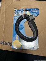 One Trip Grip black plastic bag carrier handle attached to original packaging showing branding and use instructions.