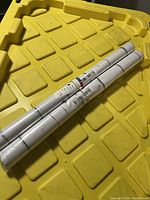 Two rolls of black and white peel and stick wallpaper placed on a yellow plastic case, showing size and labels.