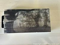 Small wooden wall sign with the quote 'Family is not an important thing, it's everything.' on a gray weathered wood plank background.