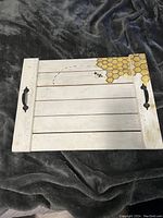 Top view of the wooden stove top cover showing honeycomb pattern and black handles on both sides, placed on dark fabric background.