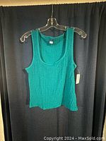Front view of teal women's tank top on plastic hanger showing fabric texture and tags.