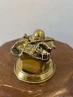 Top angle view of gilt bronze brass inkwell featuring horse saddle, jockey helmet and riding crop detailing on round base.