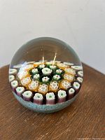 Front view of the Murano Italian Millefiori glass paperweight showing the floral millefiori pattern inside the clear glass sphere, highlighting the colors and details.