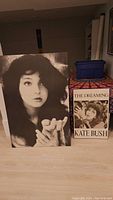 Large and smaller black and white professionally mounted prints of Kate Bush on floor, showing size difference and overall condition