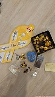 Overview photo of all items showing brass buttons in black box, gold anchor pins, badges, Zippo lighter, and support troops sash
