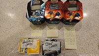 Photo of three Pokémon card tins featuring Lapras and Charizard, three labeled plastic bags containing energy cards and code cards, and loose cards.