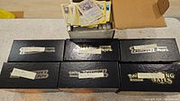 Seven black boxes labeled with Pokémon expansion names including Shining Fates and Champion's Path, containing trading cards.