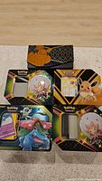 Four collectible Pokémon tins featuring artwork of Venusaur, Eevee, Crobat, and Lilligant shown closed on tabletop.