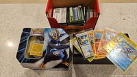 Photo of Pokemon Empoleon tin, assorted loose, laminated, and holographic cards, and box of code cards