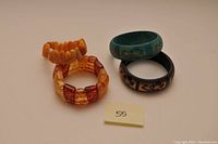 Four bangles shown together: two bead bracelets and two rigid floral motif bangles