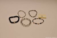 Five beaded and crystal bracelets laid out on a flat surface with a label '54'.