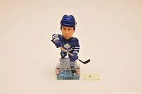 Front view of Darcy Tucker bobble head, showing detailed face and hockey gear with Maple Leafs blue uniform and labeled base.