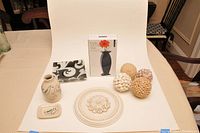 Full view of the decor lot items on table with white backdrop: ceramic vase, glass plate, boxed black vase, white wall medallion, and three decorative balls.