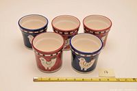 Top view of five Italian ceramic planters with bird and heart designs showing dimensions with a tape measure.